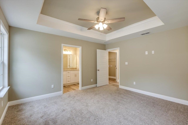 unfurnished bedroom featuring connected bathroom, a raised ceiling, and ceiling fan