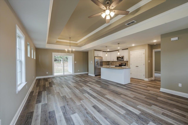 kitchen with sink, hanging light fixtures, stainless steel appliances, white cabinets, and a raised ceiling