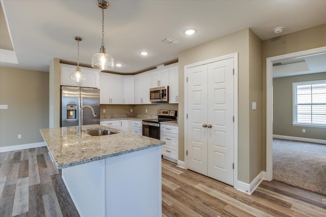 kitchen with sink, decorative light fixtures, white cabinets, and appliances with stainless steel finishes