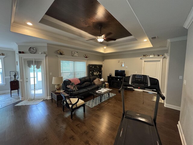 living room featuring baseboards, ceiling fan, a tray ceiling, and dark wood-type flooring