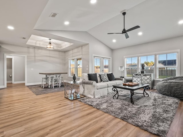 living room featuring light hardwood / wood-style floors, a raised ceiling, and ceiling fan