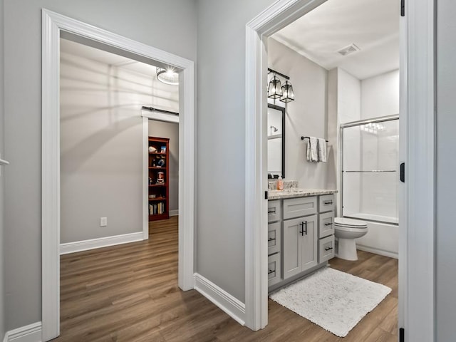 full bathroom featuring hardwood / wood-style floors, vanity, toilet, and enclosed tub / shower combo