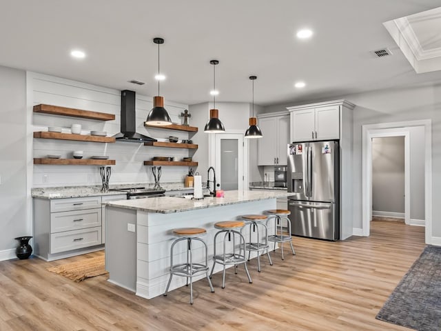 kitchen featuring light stone countertops, appliances with stainless steel finishes, a kitchen breakfast bar, wall chimney range hood, and pendant lighting