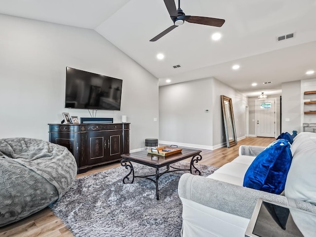 living room with ceiling fan, vaulted ceiling, and light wood-type flooring