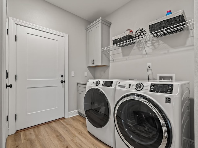 washroom with washer and clothes dryer, light hardwood / wood-style floors, and cabinets