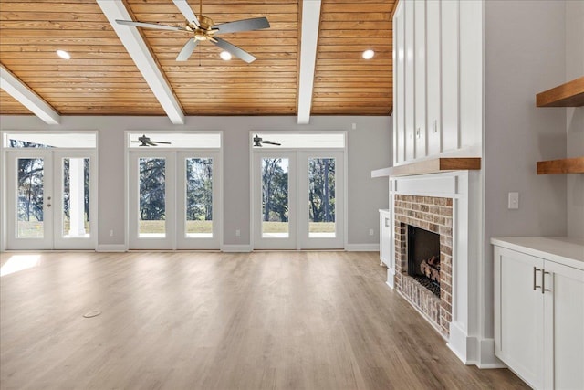 unfurnished living room featuring a fireplace, french doors, wooden ceiling, and light hardwood / wood-style flooring