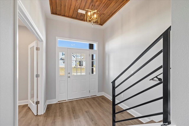 foyer entrance featuring light hardwood / wood-style flooring, wood ceiling, and a notable chandelier