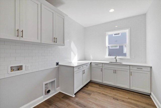 laundry area with light hardwood / wood-style floors, washer hookup, electric dryer hookup, sink, and cabinets