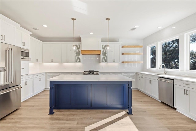 kitchen with decorative light fixtures, a kitchen island, premium range hood, appliances with stainless steel finishes, and white cabinets