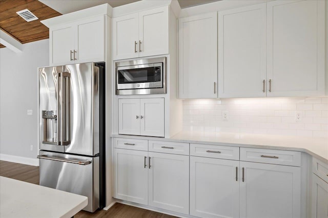 kitchen with dark hardwood / wood-style flooring, decorative backsplash, stainless steel appliances, and white cabinetry