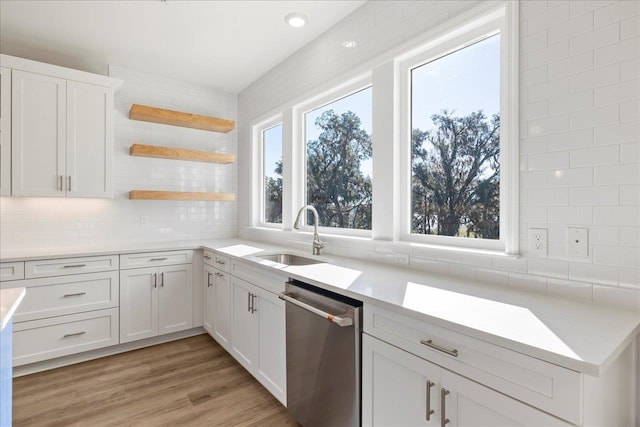 kitchen with white cabinetry, stainless steel dishwasher, sink, and tasteful backsplash