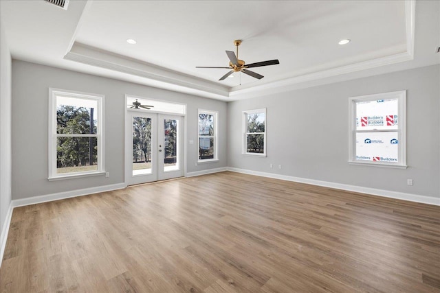 empty room with french doors, light hardwood / wood-style flooring, and a raised ceiling