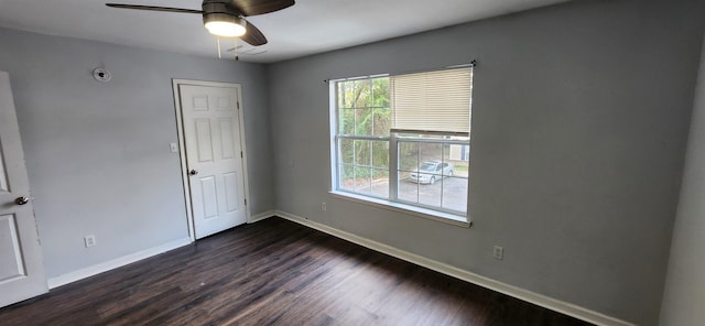 spare room with dark wood-type flooring, ceiling fan, and a healthy amount of sunlight