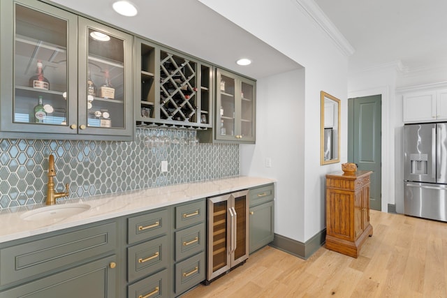 bar with crown molding, wet bar, a sink, and stainless steel refrigerator with ice dispenser