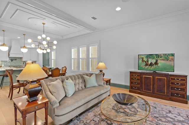 living room featuring ornamental molding, a raised ceiling, visible vents, and light wood-style floors