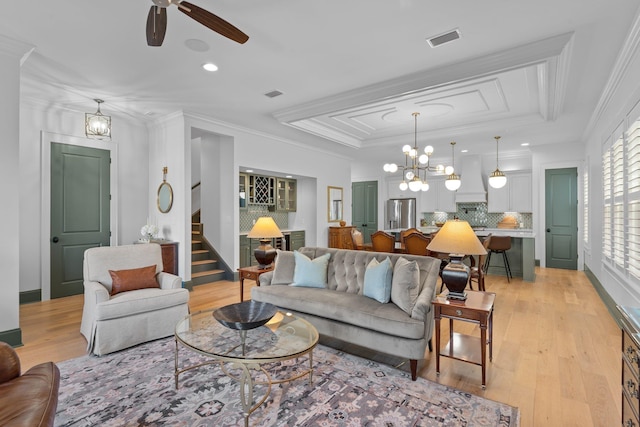 living area with ornamental molding, a raised ceiling, visible vents, and light wood-style floors