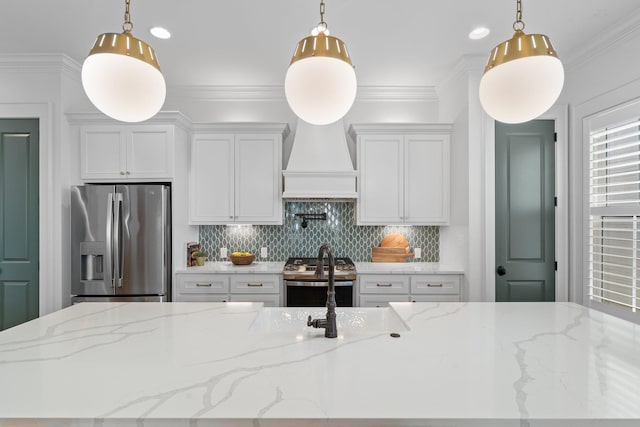 kitchen with stainless steel appliances, hanging light fixtures, and light stone countertops