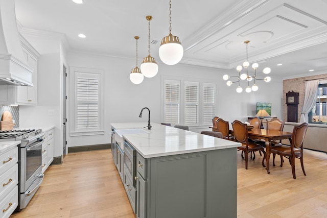 kitchen featuring white cabinets, an island with sink, gray cabinetry, a sink, and gas stove