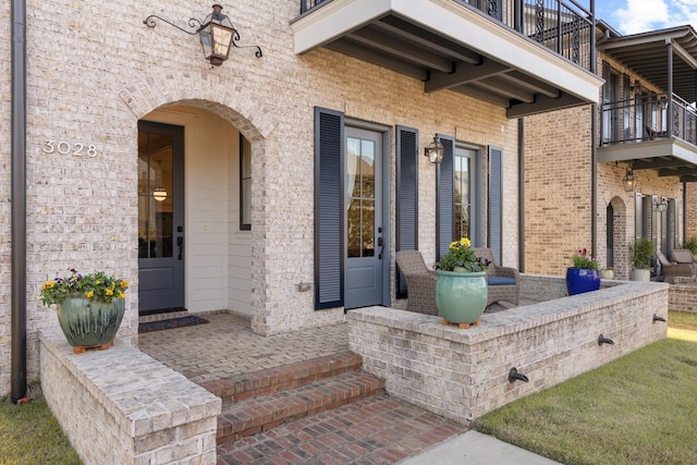 doorway to property with brick siding, a patio, and a balcony