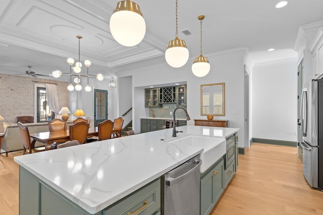 kitchen with pendant lighting, a center island with sink, stainless steel appliances, a sink, and light wood-type flooring