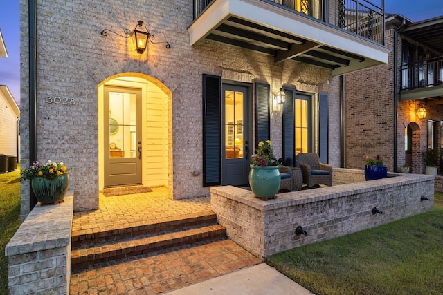 view of exterior entry featuring a patio area and brick siding