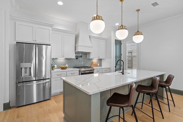 kitchen with visible vents, white cabinets, a kitchen island with sink, custom exhaust hood, and stainless steel appliances