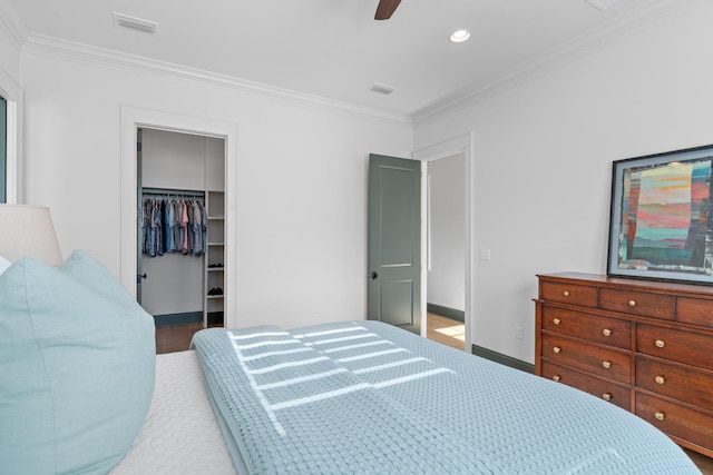 bedroom featuring visible vents, crown molding, a spacious closet, and baseboards