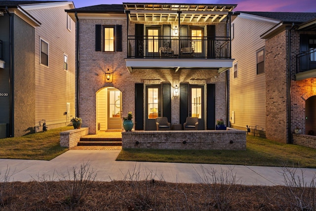 view of front of house with brick siding, a porch, a balcony, and a pergola