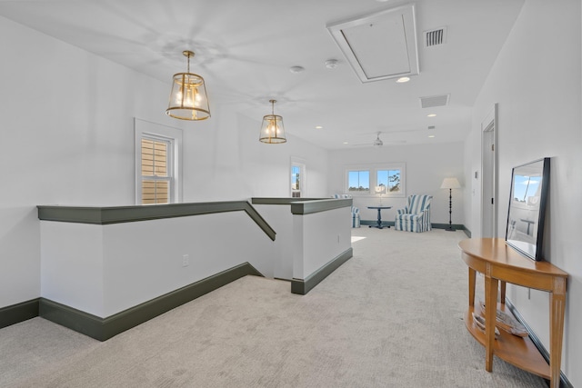 hallway with carpet floors, an upstairs landing, baseboards, visible vents, and attic access