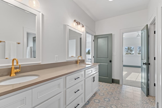 full bath with a sink, baseboards, and double vanity