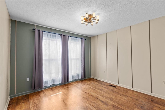 310 Glenridge Rd, Perry, FL 32348 - spare room with a chandelier, a textured ceiling, wood finished floors, and a decorative wall