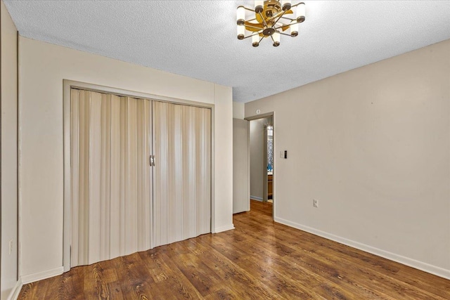 310 Glenridge Rd, Perry, FL 32348 - unfurnished bedroom with a chandelier, wood finished floors, a closet, baseboards, and a textured ceiling