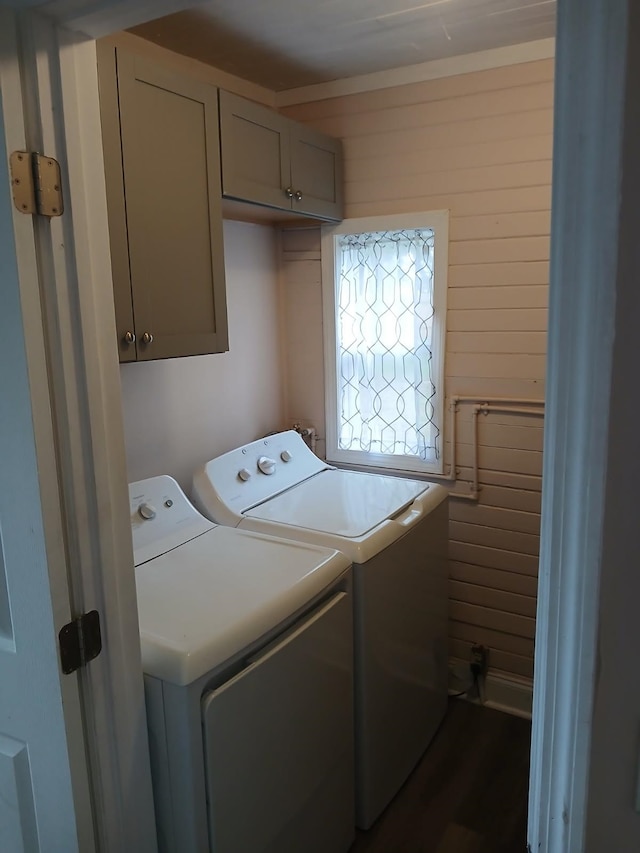 washroom with wooden walls, washing machine and dryer, and cabinets