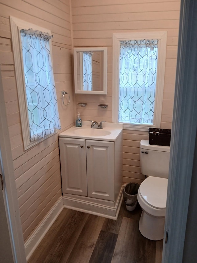 bathroom featuring vanity, hardwood / wood-style floors, wood walls, and toilet