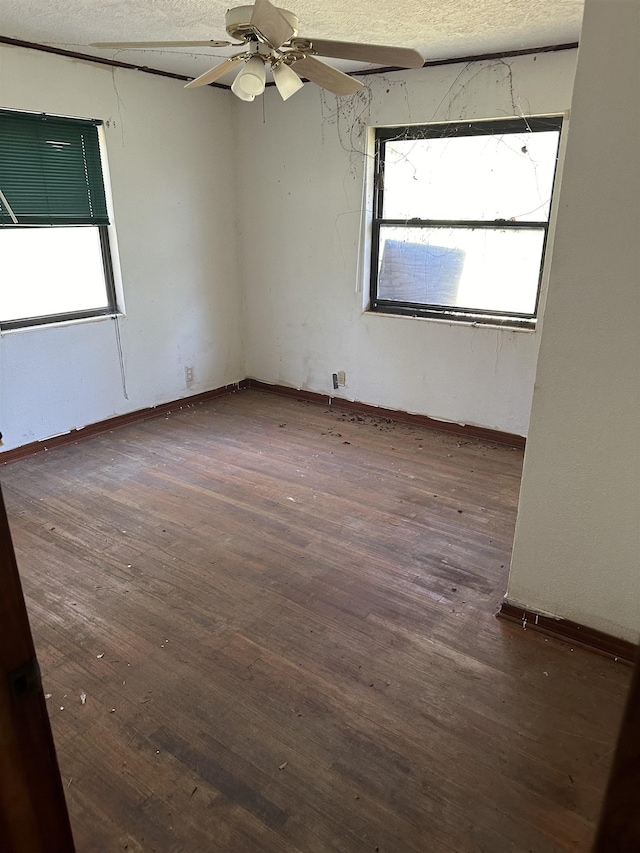 empty room featuring baseboards, a ceiling fan, wood finished floors, and a textured ceiling