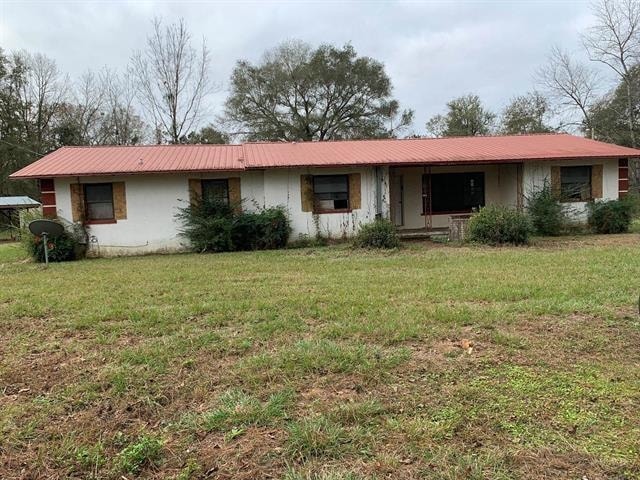 ranch-style house with stucco siding, metal roof, and a front yard