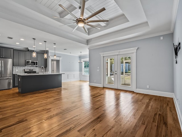 unfurnished living room featuring hardwood / wood-style flooring, ornamental molding, a tray ceiling, and french doors