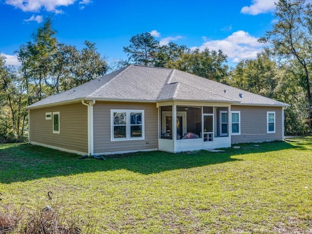 rear view of house featuring a yard and a sunroom