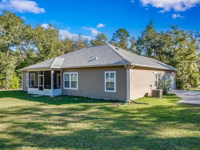 rear view of house with a sunroom, cooling unit, and a lawn