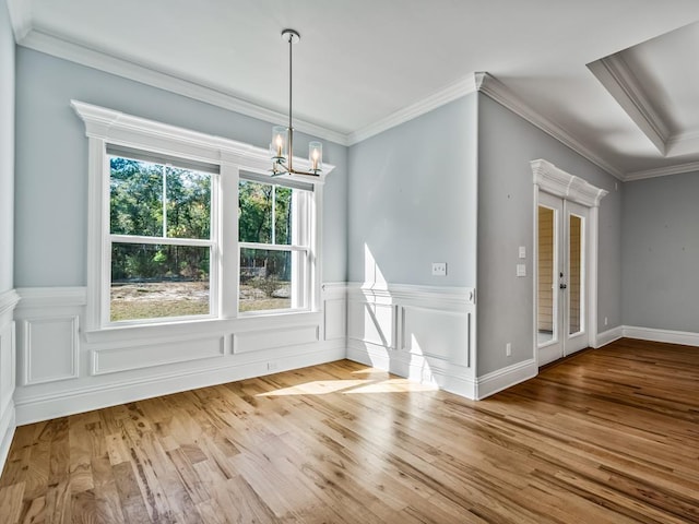 unfurnished dining area featuring crown molding, a notable chandelier, and light wood-type flooring