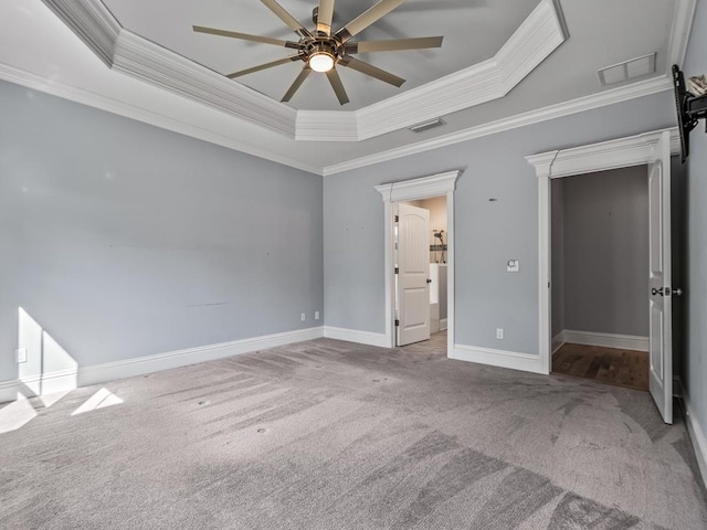 unfurnished bedroom featuring crown molding, a tray ceiling, light colored carpet, and ceiling fan