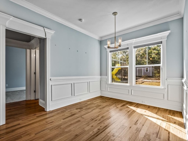 unfurnished dining area featuring hardwood / wood-style flooring, ornamental molding, and a chandelier