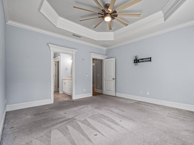 unfurnished bedroom featuring crown molding, connected bathroom, a tray ceiling, and carpet floors