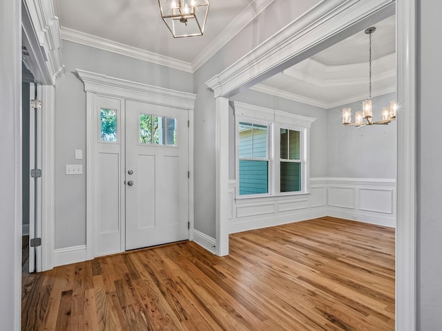 foyer entrance featuring an inviting chandelier, crown molding, and hardwood / wood-style floors