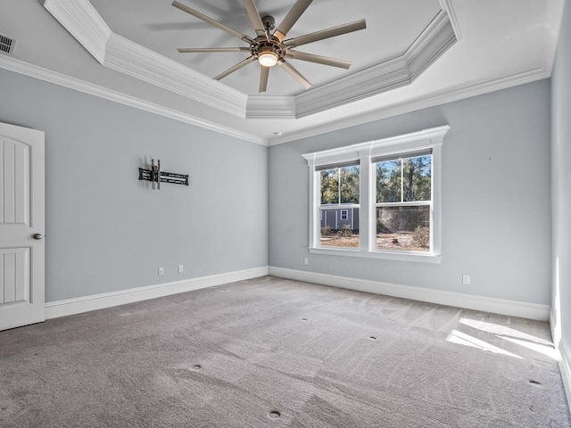 empty room with ceiling fan, light colored carpet, ornamental molding, and a tray ceiling