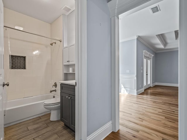 full bathroom with crown molding, hardwood / wood-style floors, vanity, tiled shower / bath, and toilet