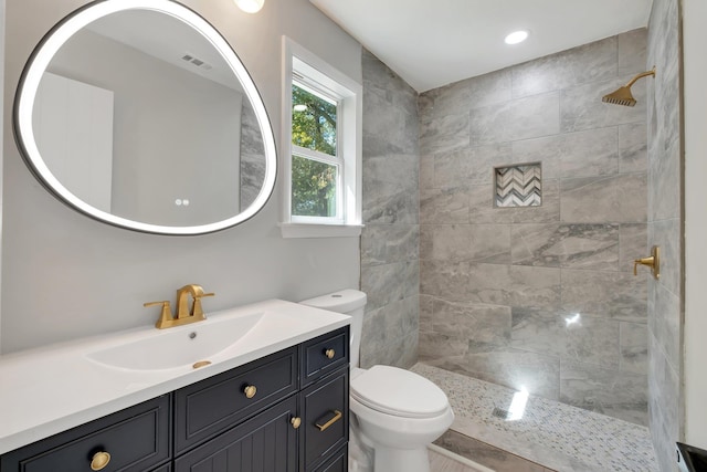 bathroom with toilet, vanity, and tiled shower