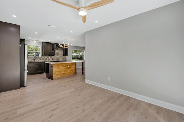 kitchen with tasteful backsplash, light wood-type flooring, stainless steel fridge, and a kitchen island