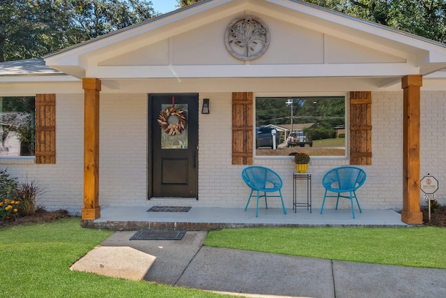 doorway to property featuring covered porch and a yard