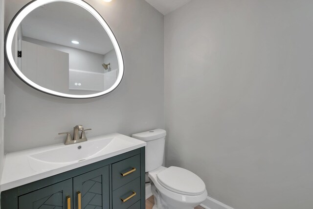 bathroom featuring toilet, vanity, and walk in shower